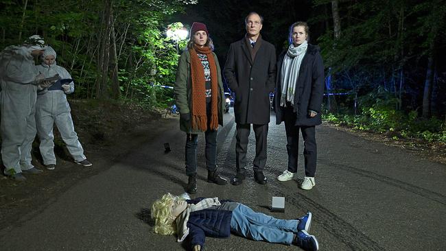 Das Ermittlerteam Karin Gorniak, Peter Michael Schnabel und Leo Winkler steht nachts auf einer Landstraße vor einem abgesperrten Bereich, während eine Attrappe in der Form eines Kindes reglos auf der Straße liegt.