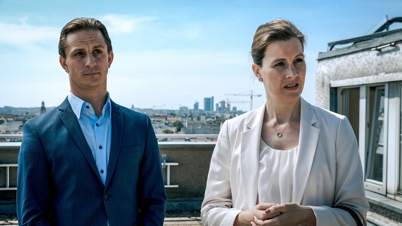 Lukas Kragl im blauen Anzug und Dr. Maria Digruber im weißen Blazer stehen auf einer Dachterrasse über Wien.