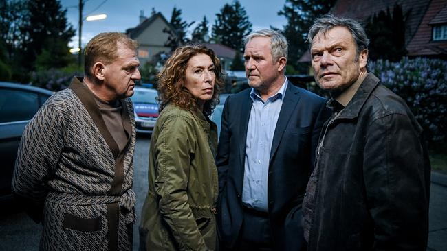 © ORF/Hubert Mican Rudolf "Purzl" Haag, Bibi Fellner, Moritz Eisner und Stefan Pohl stehen draußen bei Dämmerung zusammen und schauen in unterschiedliche Richtungen, vor einer Wohnsiedlung mit Bäumen im Hintergrund.