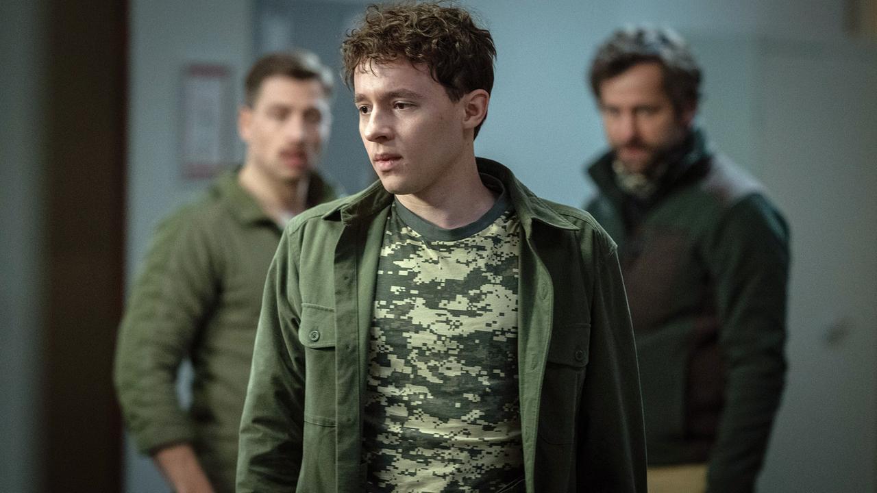 Mats Zechmann, ein junger Mann in Tarnkleidung, steht mit den zwei Männern Julian Verhage und Mats Vater Moritz Zechmann in einem Raum beim Überlebenstraining im Bunker.