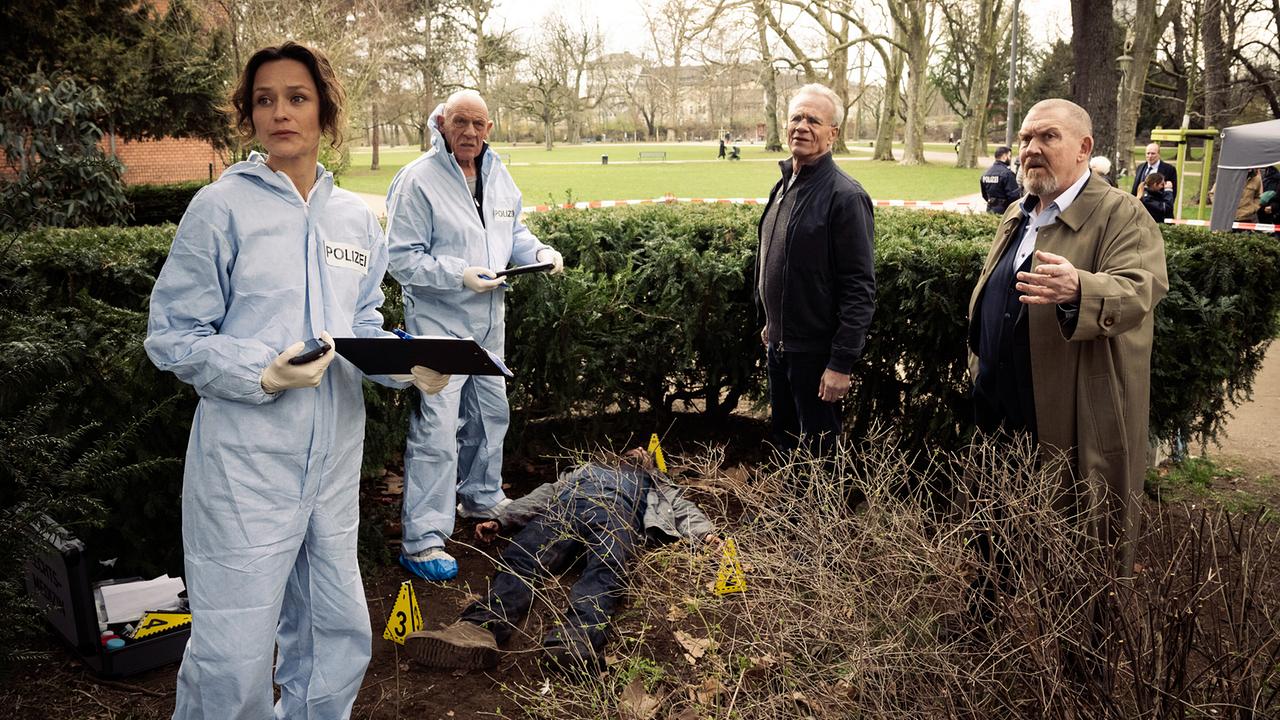 Am Rand eines Kölner Stadtparks wurde ein Mann ermordet. Die KTU-Chefin Natalie Förster, der Rechtsmediziner Dr. Roth und die Kommissare Max Ballauf und Freddy Schenk am abgesperrten Tatort.