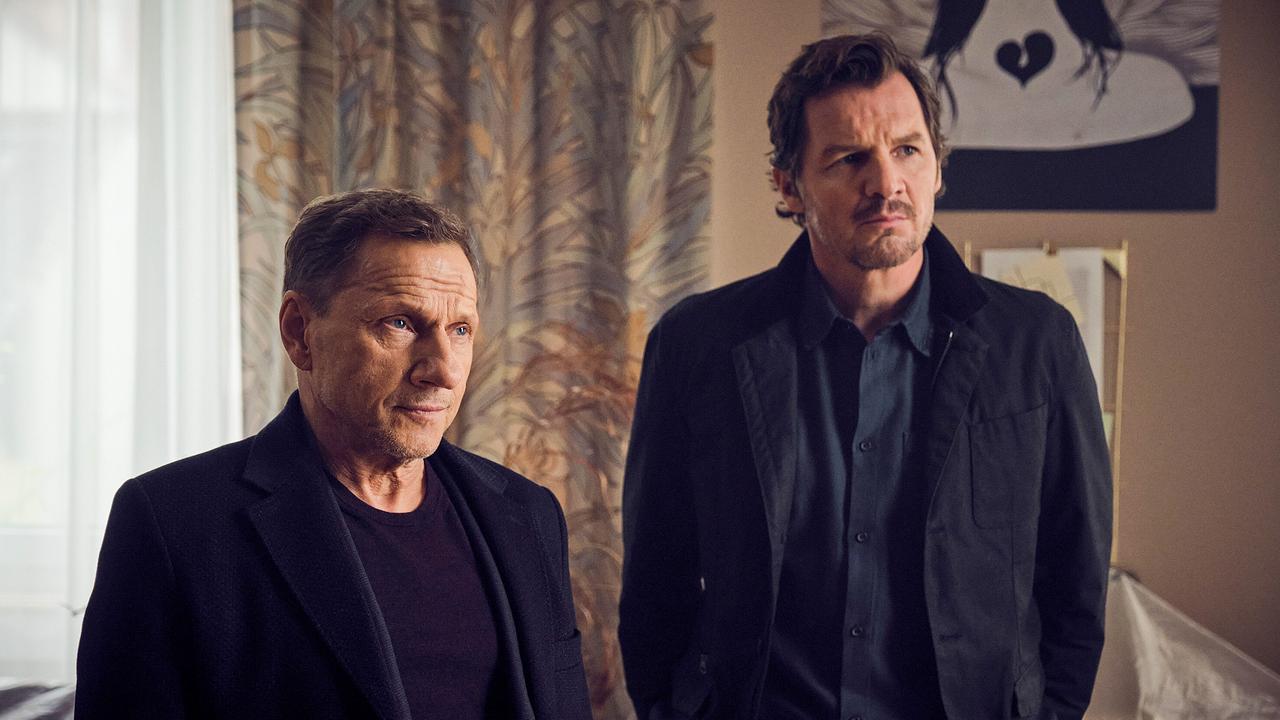 Thorsten Lannert und Sebastian Bootz stehen ernst in einem Zimmer.