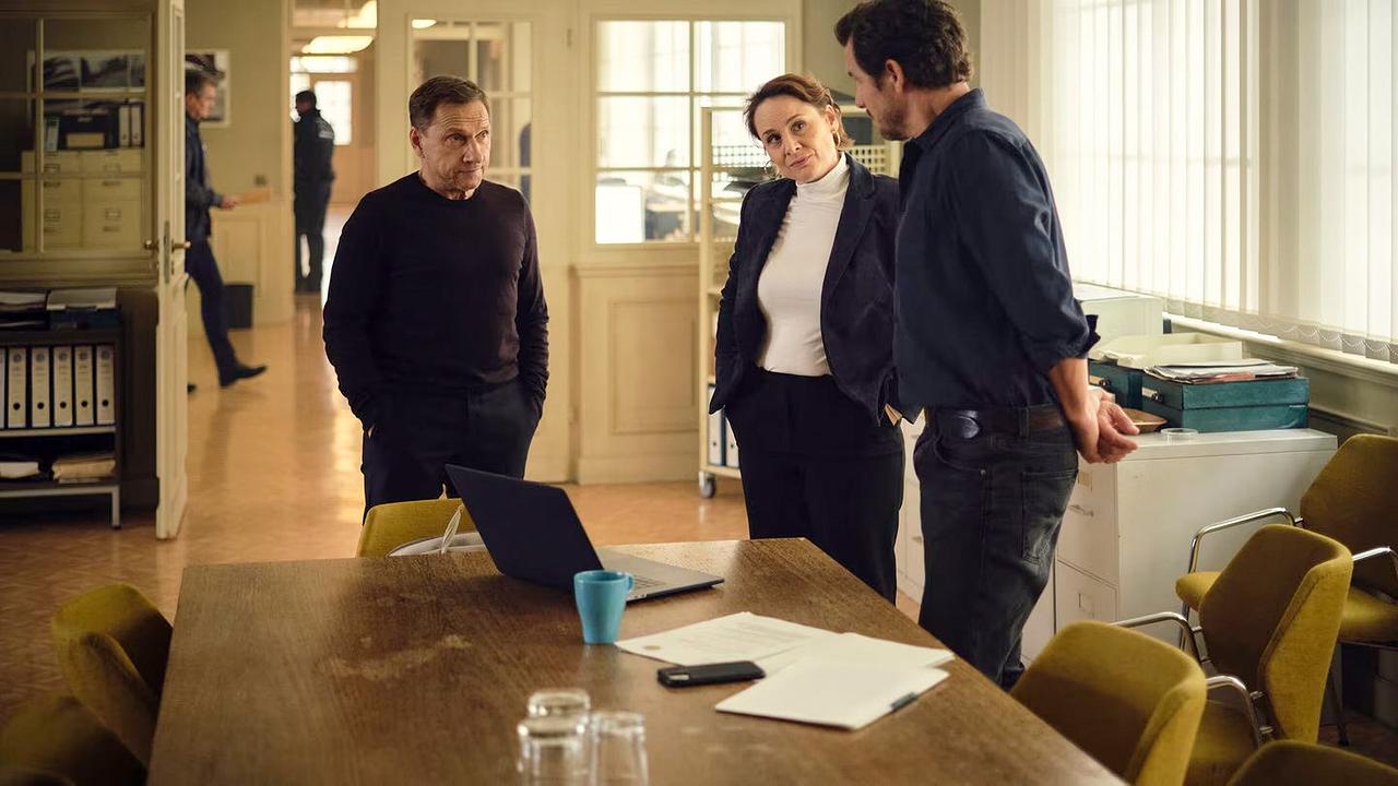 Eva Möbius, Thorsten Lannert und Sebastian Bootz stehen in einem hellen Büroraum an einem Besprechungstisch.