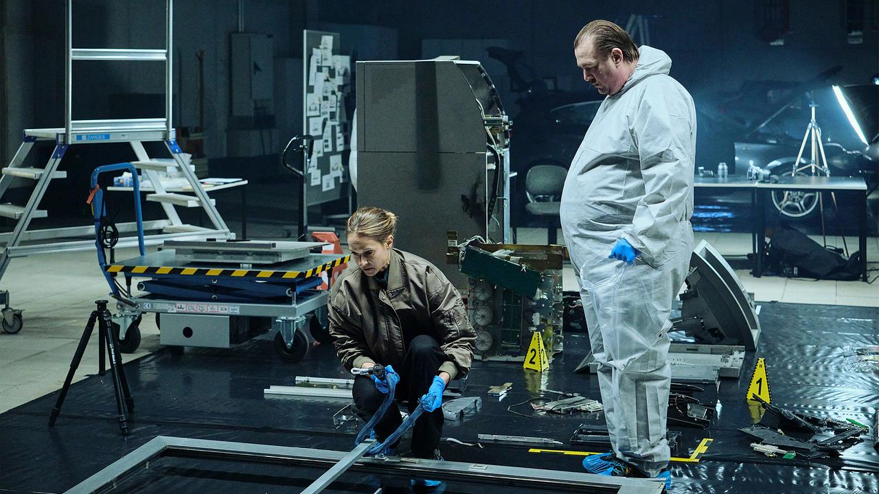 Johanna Stern und ein Kriminaltechniker in Schutzkleidung und mit Handschuhen untersuchen die Trümmerteile des gesprengten Geldautomats in der Kriminaltechnik.