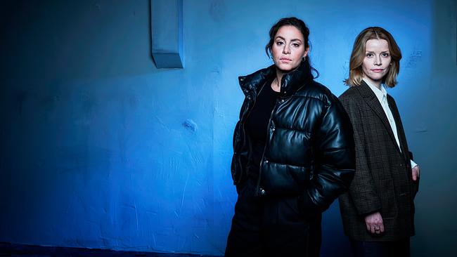 Mila Sahin und Elli Krieger stehen vor einer blau beleuchteten Wand.