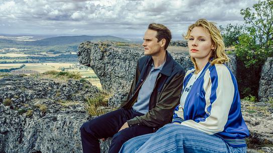 Kriminalhauptkommissar Felix Voss und Kriminalhauptkommissarin Emmy Rathgeber sitzen auf einer felsigen Anhöhe auf dem Staffelberg und blicken über die Landschaft.