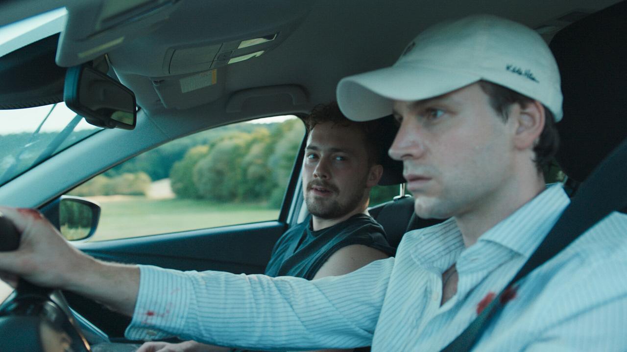 Marcel und Toni fahren mit ernsten Mienen in einem Auto durch Gottesgarten. 