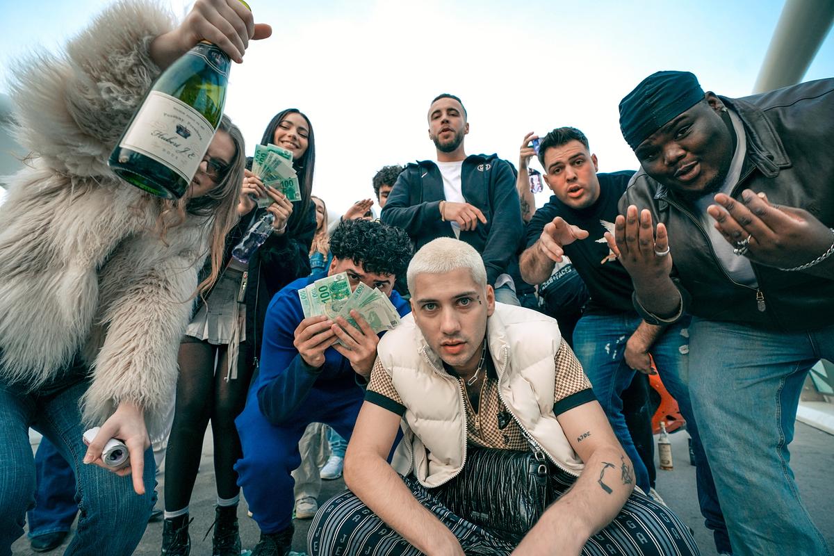Eine Gruppe junger Rapper posiert im Freien mit Geldscheinen und einer Sektflasche um Theodor „Ted“ Sänftner im Vordergrund.