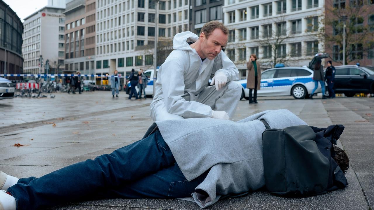 "Tatort: Vier Leben":  Robert Karow (Mark Waschke) betrachtet am Tatort die Leiche des ehemaligen Politikers Jürgen Weghorst (Philipp Lind, vorne).