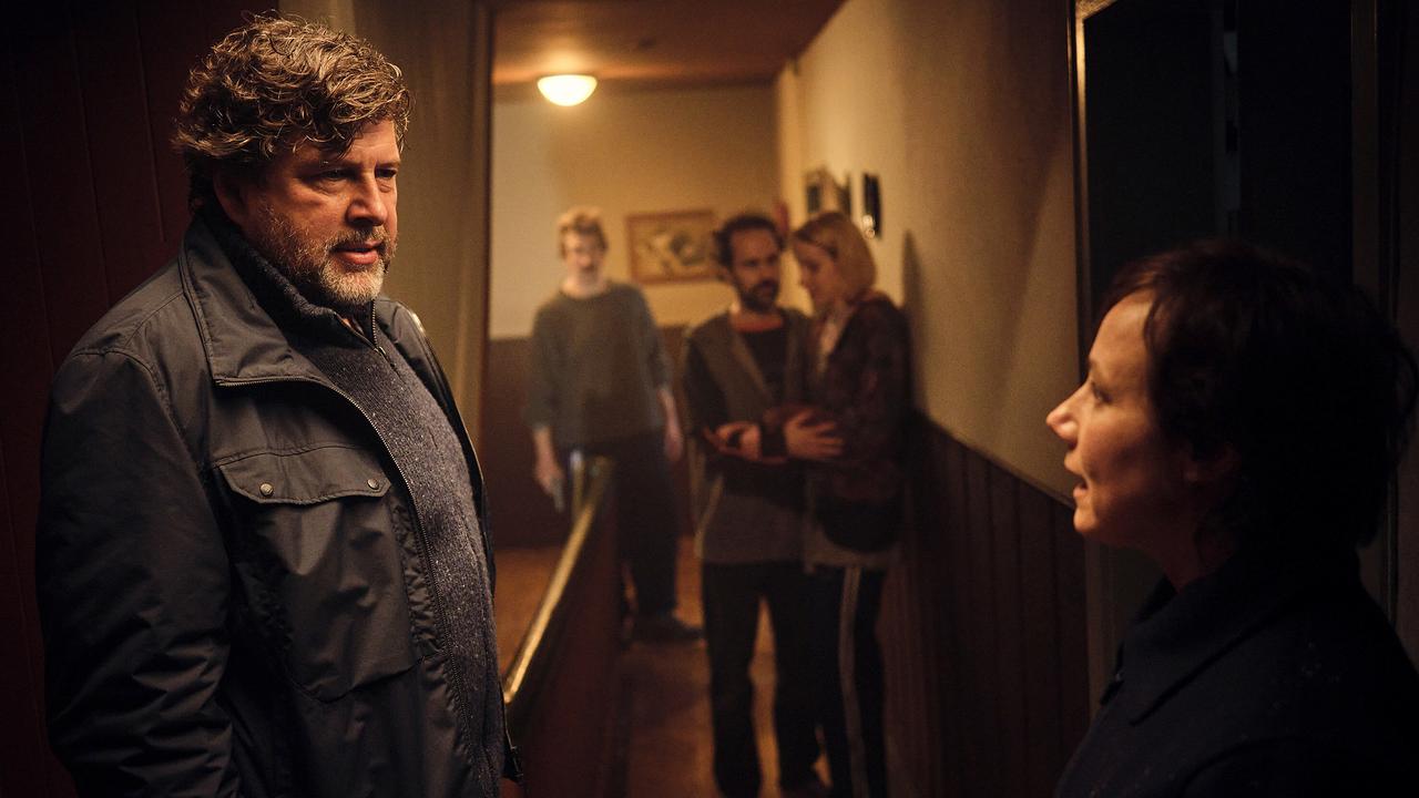 Hans-Jochen Wagner und Eva Löbau stehen im schmalen Flur und sprechen miteinander, im Hintergrund weitere Menschen.