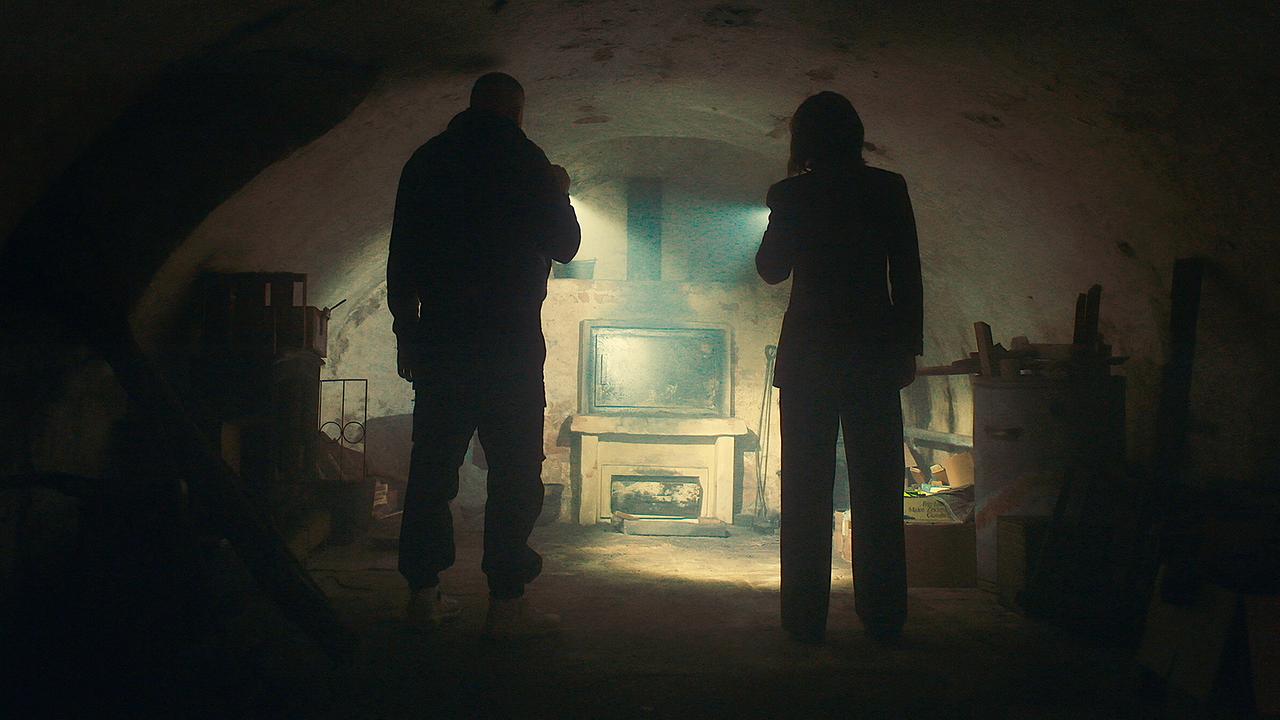 © ORF/HR/Sommerhaus Edin Hasanovic und Melika Foroutan mit Taschenlampen erkunden einen niedrigen, dunklen Raum eines Kellergewölbe.