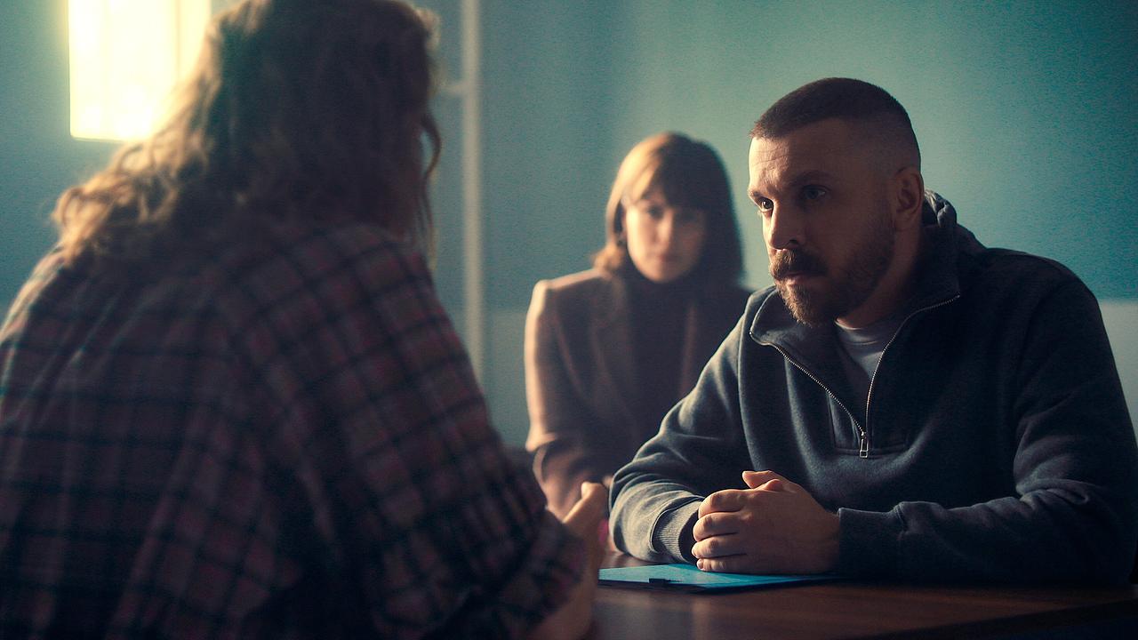 © ORF/HR/Sommerhaus Maren Eggert und Edin Hasanovic sitzen an einem Tisch in einem spärlich beleuchteten Raum, Melika Foroutan beobachtet die beiden im Hintergrund.