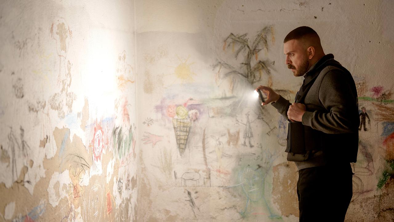 © ORF/HR/Sommerhaus/Daniel Dornhöfer Edin Hasanovic beleuchtet mit seinem Handy bunte Kinderzeichnungen an einer Wand.