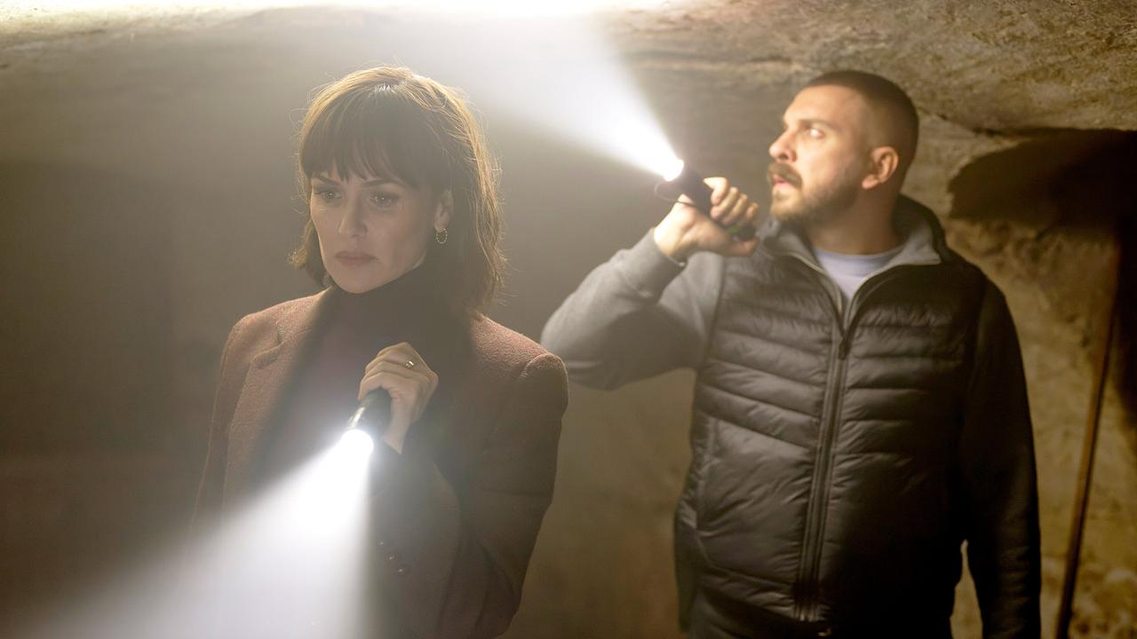 © ORF/HR/Sommerhaus/Daniel Dornhöfer Melika Foroutan und Edin Hasanovic mit Taschenlampen erkunden ein niedriges, dunkles Kellergewölbe.