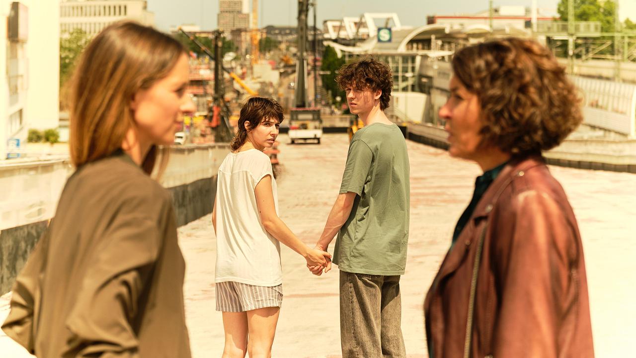 Auf der Baustelle einer Ludwigshafener Brücke halten sich Nisha und Mike an der Hand und blicken zurück, während Lena Odenthal und Johanna Stern im Vordergrund stehen.