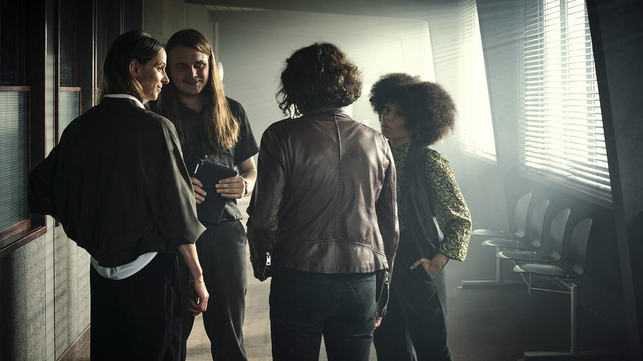 Johannes Scheidweiler, Davina Chanel Fox stehen mit Lisa Bitter und Ulrike Folkerts stehen in einem von Sonnenlicht durchfluteten Flur und unterhalten sich.