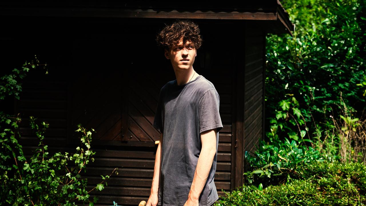 Mike steht im Sonnenschein vor einem kleinen Holzschuppen im Garten.