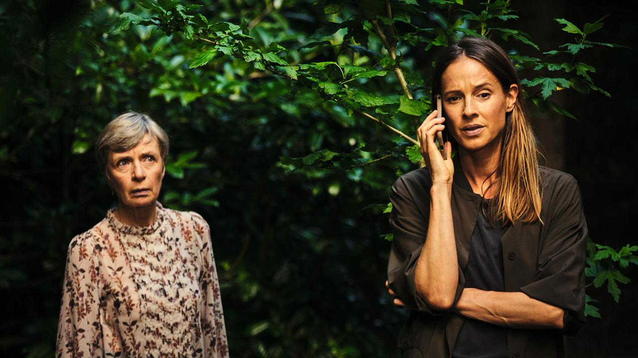 Gerlinde und Johanna, die telefoniert, stehen vor dichten Büschen.