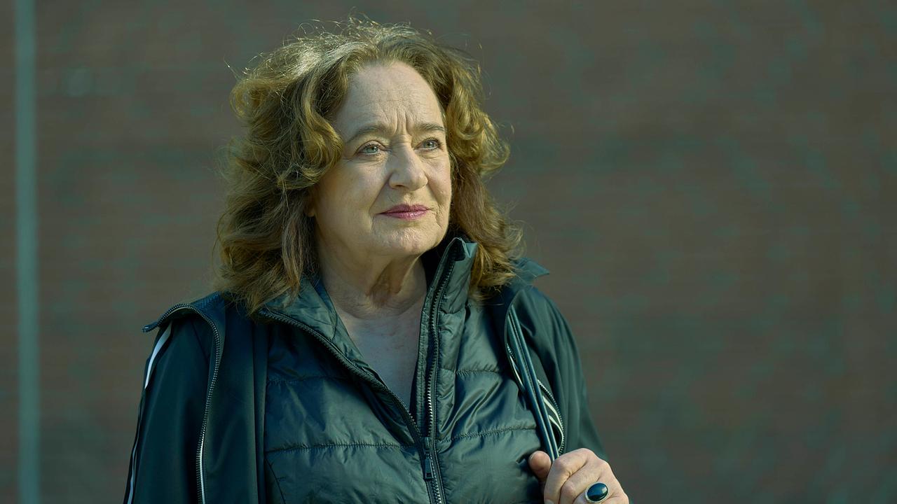 Staatsanwältin Wilhelmine Klemm in einem Anorak mit Tasche vor Backsteinwand.