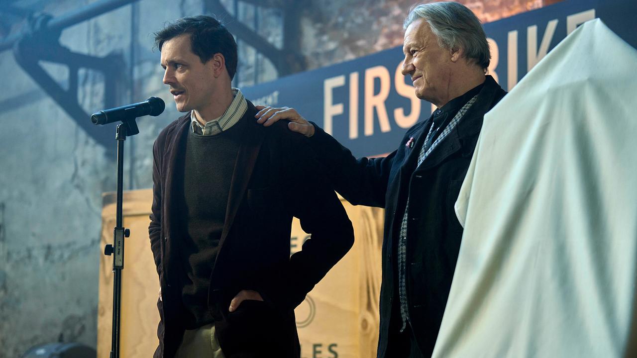 Kurt Hobrecht sen. und sein Sohn Konstantin Hobrecht vor einem Mikro auf der Bühne bei der Präsentation von Hobrechts "First Bike".