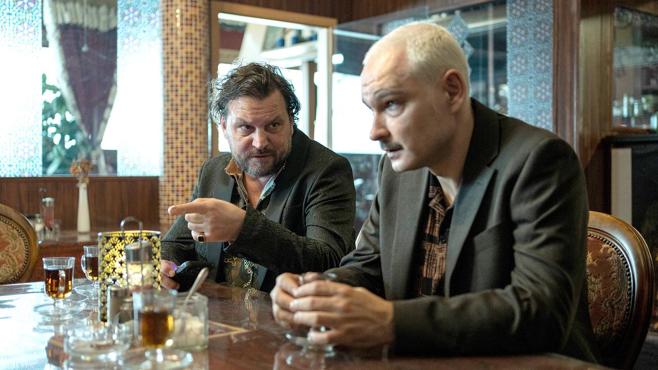 Zoric sitzt neben Joe Glauning an einem Tisch in einem orientalisch dekorierten Raum und trinken Tee.