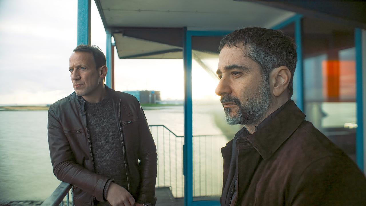 Thorsten Falke und Mario Schmitt stehen auf einer Terrasse mit Blick auf ein Gewässer im Hintergrund.