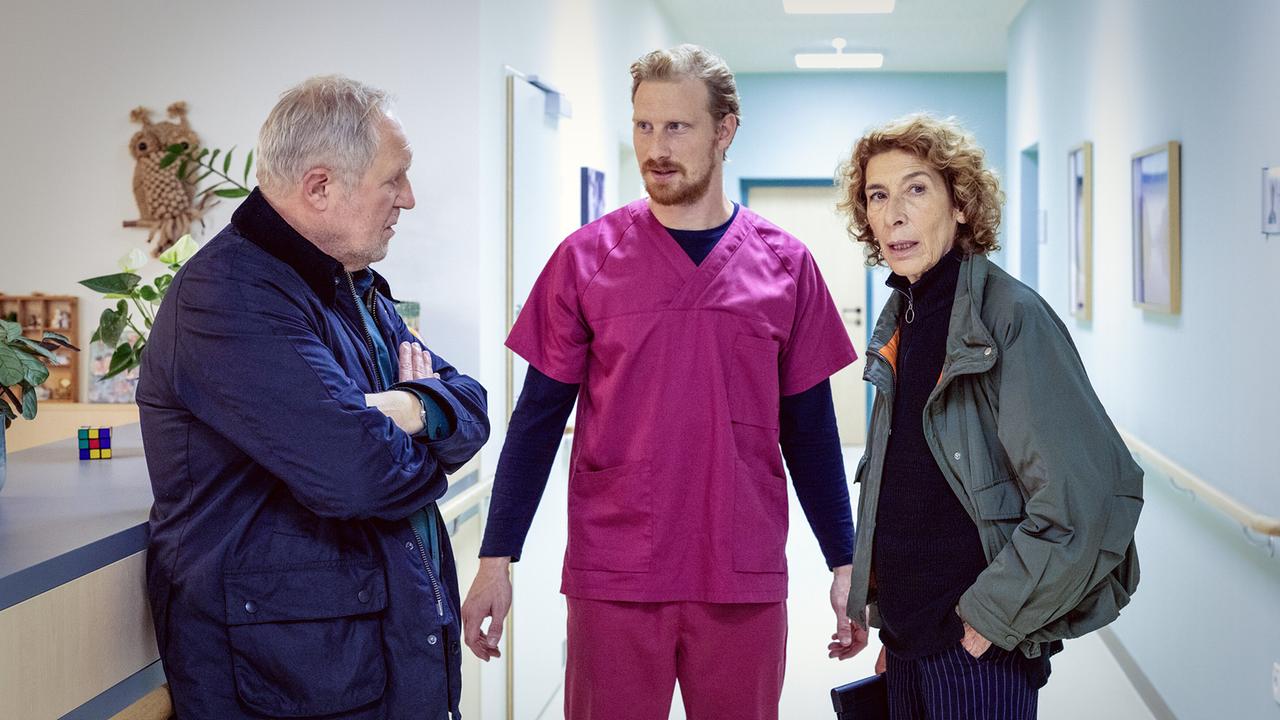 Moritz Eisner und Bibi Fellner reden mit dem Pfleger Horst Windisch im Flur im Pflegeheim