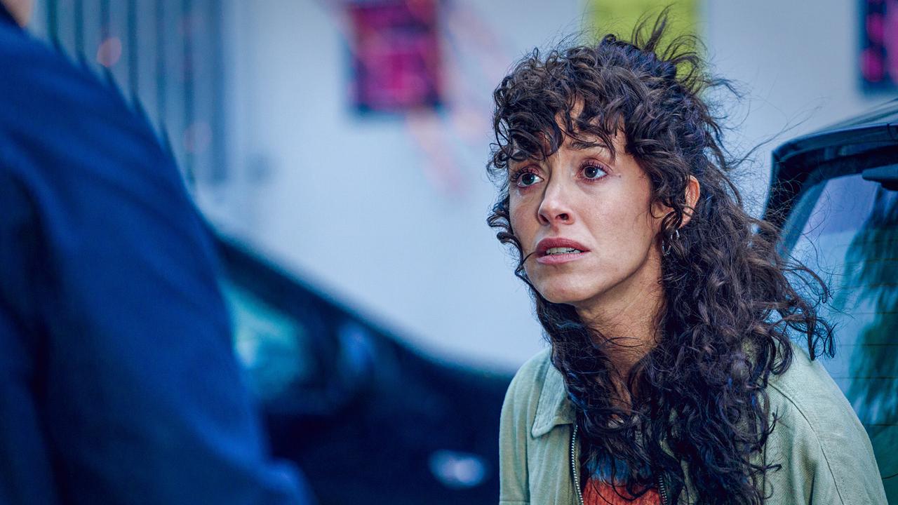 Linda Filipovic mit lockigem Haar steht im Freien und unterhält sich mit einer weiteren Person.