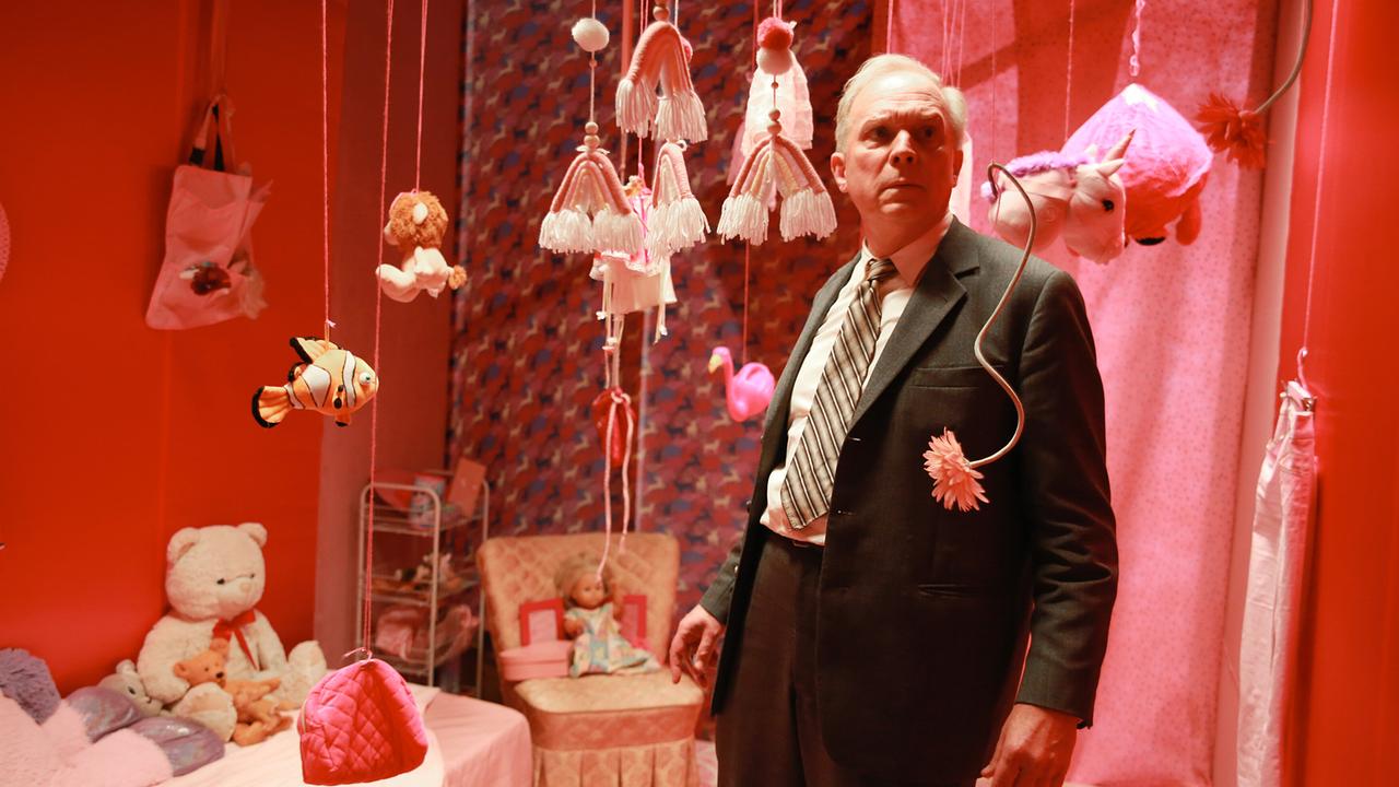 Kommissar Felix Murot steht in einem pink dekorierten Kinderzimmer zwischen hängendem Spielzeug.