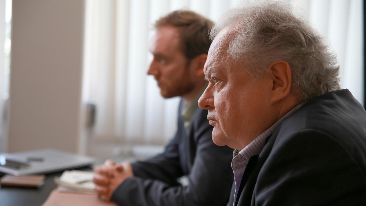 Staatsanwalt Froese und der LKA Präsident sitzen an einem Tisch und schauen konzentriert.