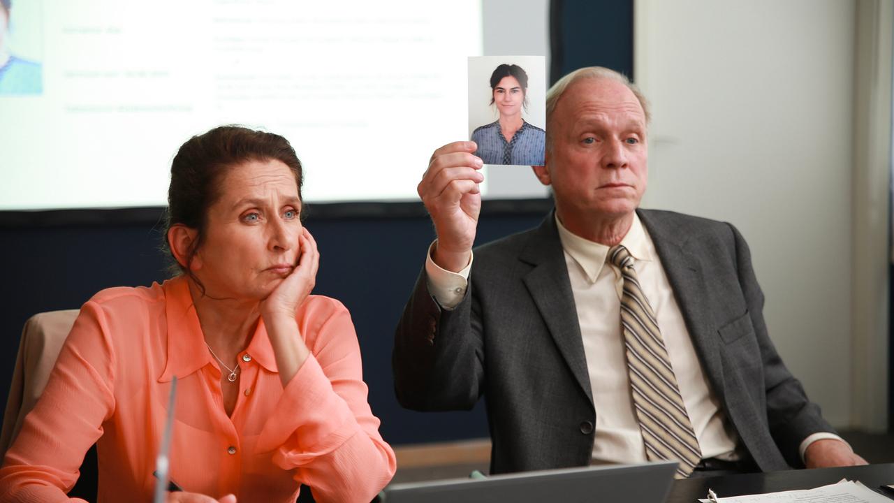 Magda Wächter und Felix Murot  sitzen in einem Besprechungsraum, während Murot ein Foto einer Frau hochhält.