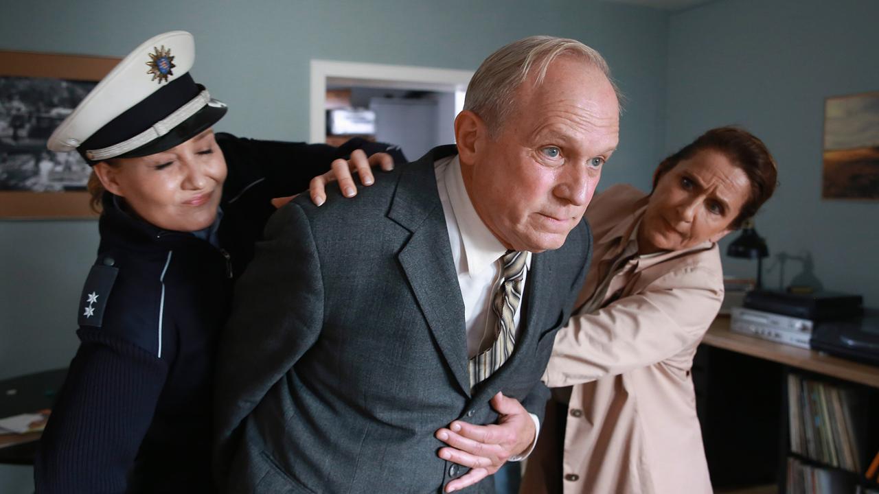 Polizistin Schreiner und Magda Wächter halten  Felix Murot im Anzug fest.