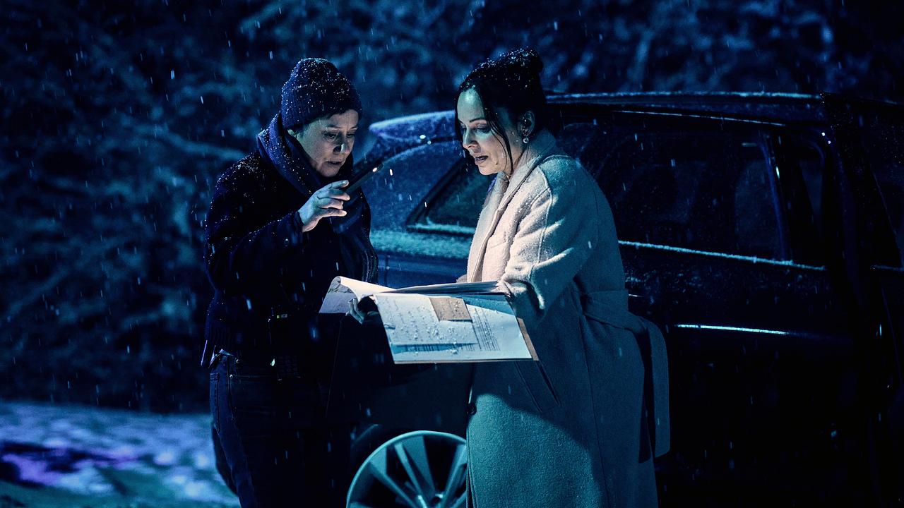 Franziska Tobler und Evelyn Kaltenstein suchen das Kind im Wald und blättern nachts bei Schneefall in einer großen Akte neben einem Auto.