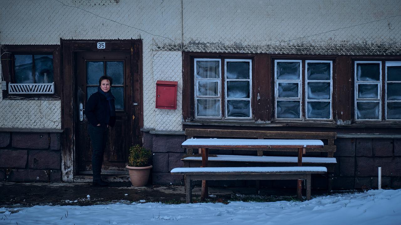Franziska Tobler steht vor dem verschneiten Eingang eines alten, witterungsgezeichneten Haus.