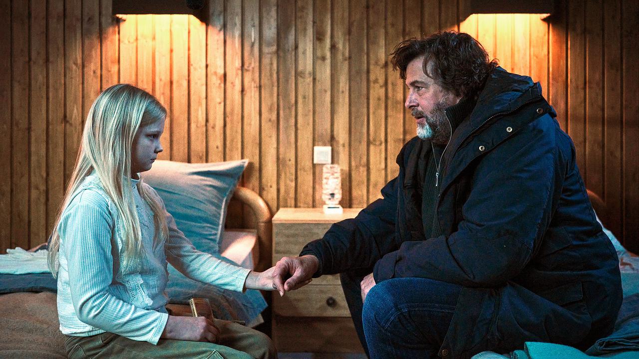 Friedemann Berg und  Eliza sitzen auf Betten und halten sich vorsichtig an den Händen.