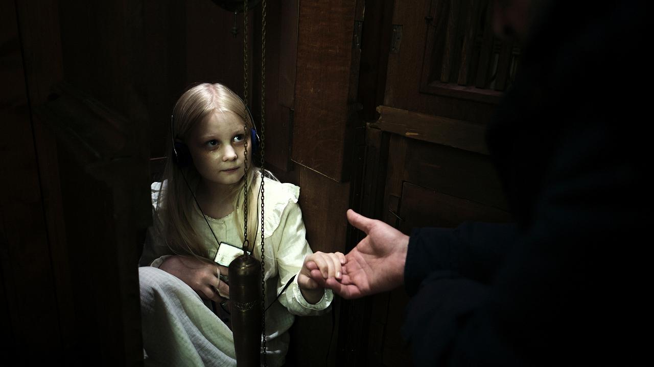 Ein in kleines Mädchen sitzt in einem Uhrenkasten, während Friedemanns Hand von außen beruhigend entgegengestreckt wird.