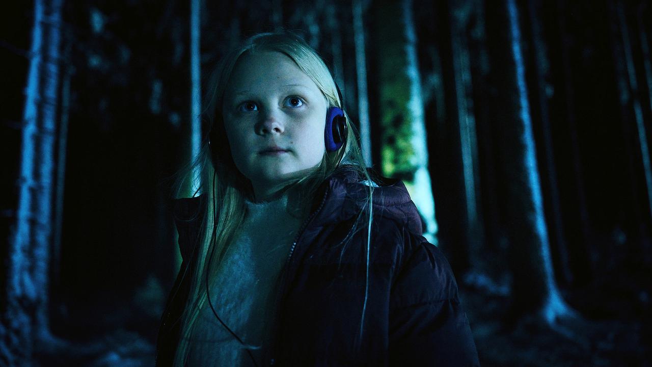 Eliza läuft mit Kopfhörern durch den nächtlichen Wald.