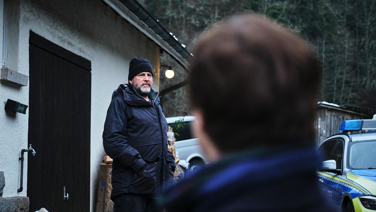 Vor einem Haus mit Polizeiwagen blicken sich Friedemann Berg und Franziska Tobler an.
