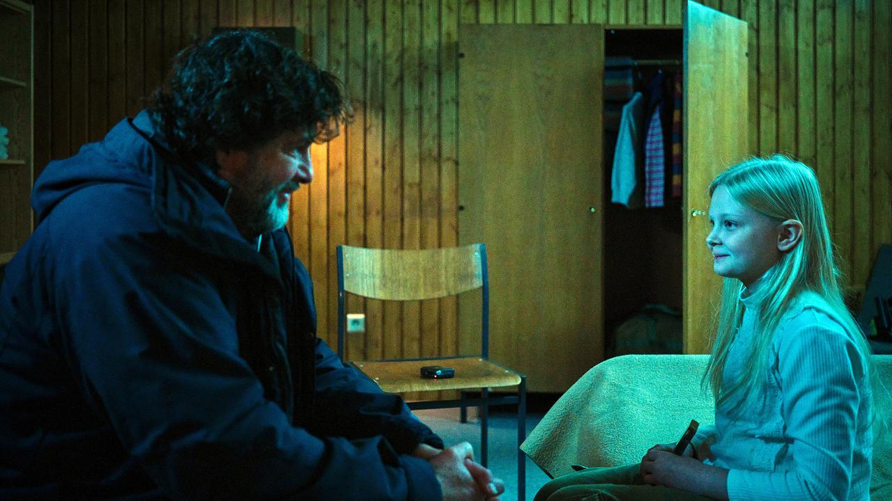 In einem nüchternen Holzraum sitzt Friedemann Berg Eliza gegenüber und sie lächeln sich an.