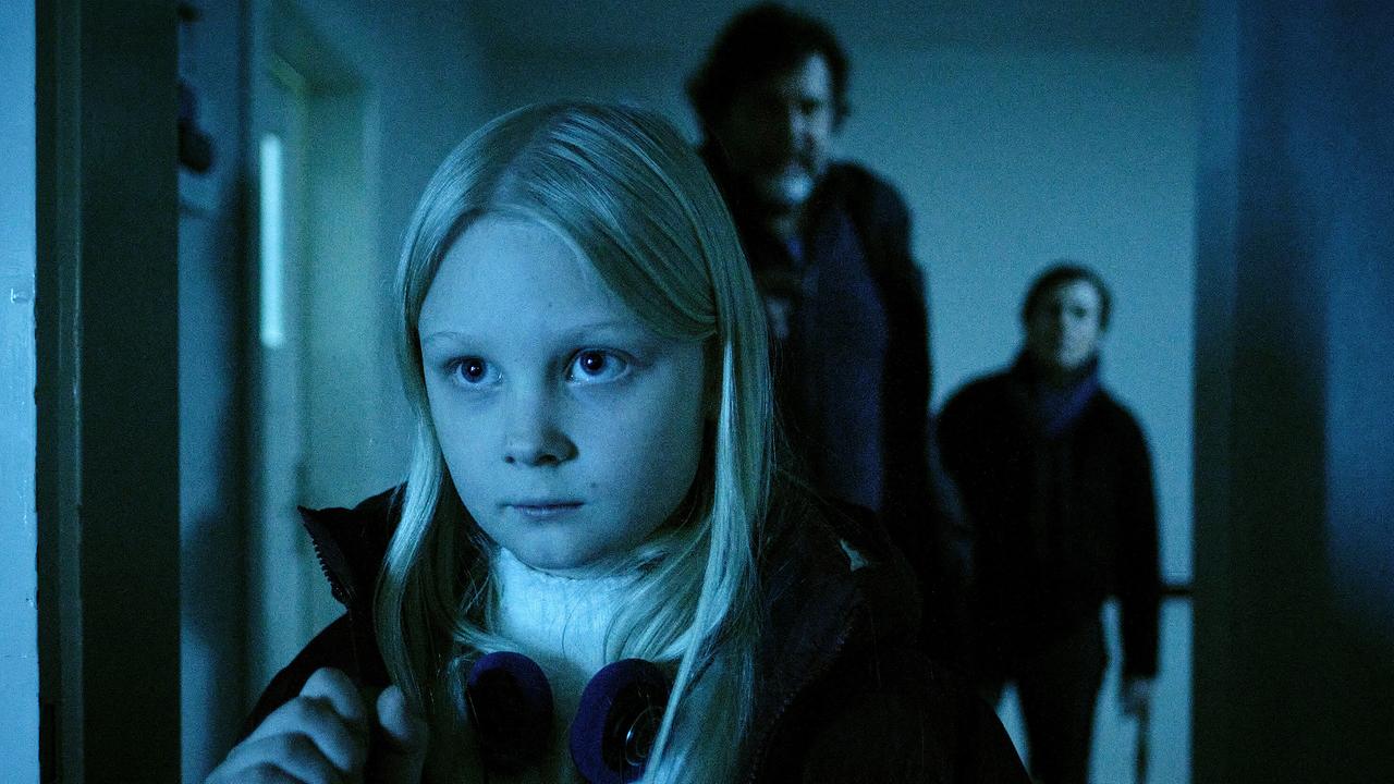 Die kleine Eliza geht durch einen dunklen Flur, gefolgt von Friedemann Berg und Franziska Tobler.