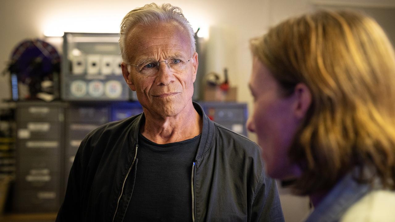 Max Ballauf befragt Eva Krüger in einem Raum voller Technik und Kabel.