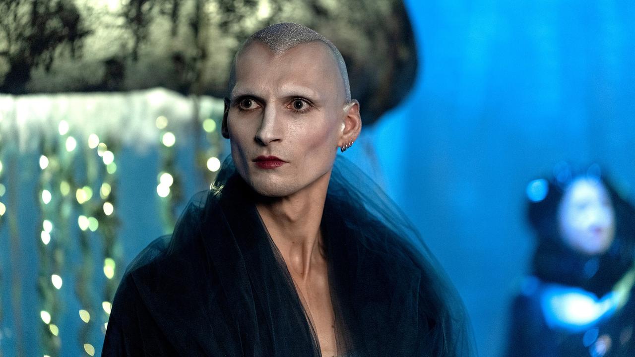 Der Countertenor David Deycks in einem dunklen, dramatischen Bühnenkostüm steht im Scheinwerferlicht.