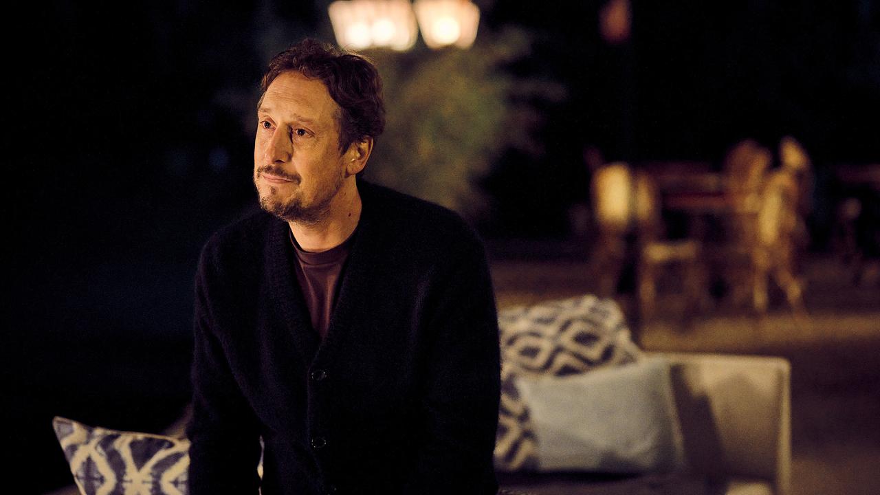 Stephan Hübner sitzt abends im Freien auf einem Sofa und wirkt in Gedanken versunken.