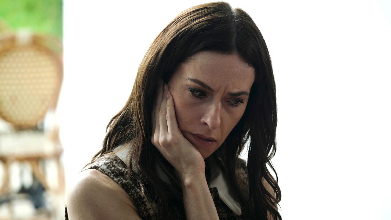 Pony sitzt nachdenklich mit der Hand am Gesicht vor hellem Hintergrund.