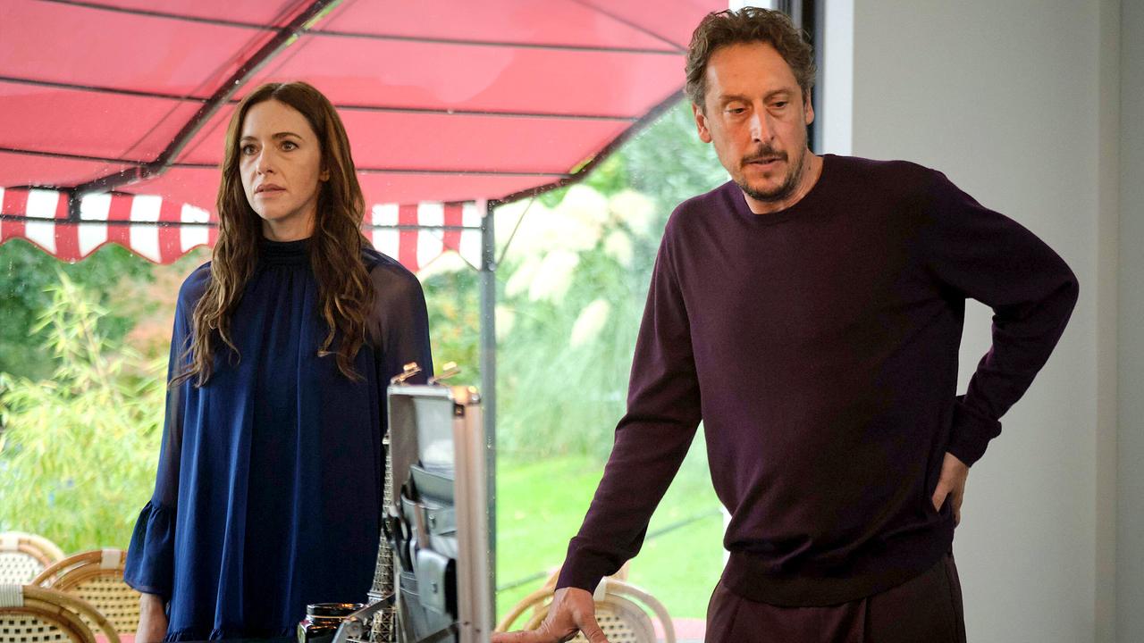 Pony und Stephan Hübner stehen in einem modernen, lichtdurchfluteten Raum mit roter Markise im Hintergrund vor einem geöffneten Koffer.