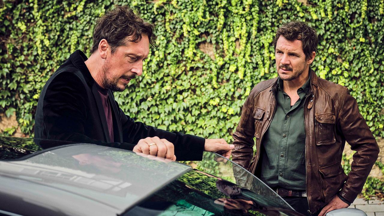 Stephan Hübner und Sebastian Bootz sprechen neben einem Auto vor einer mit Efeu bewachsenen Wand.