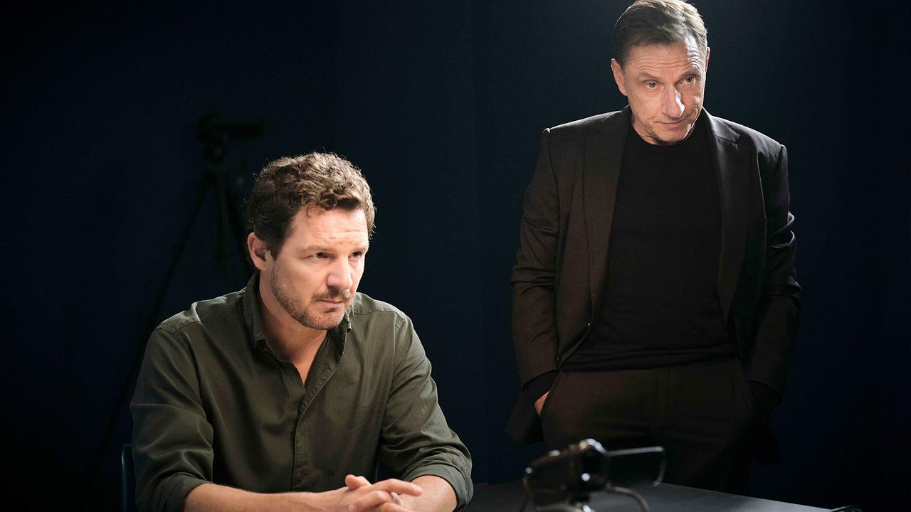 Sebastian Bootz  und Thorsten Lannert sitzen bzw. stehen am Tisch eines Verhörraums mit Mikrofon im Vordergrund.