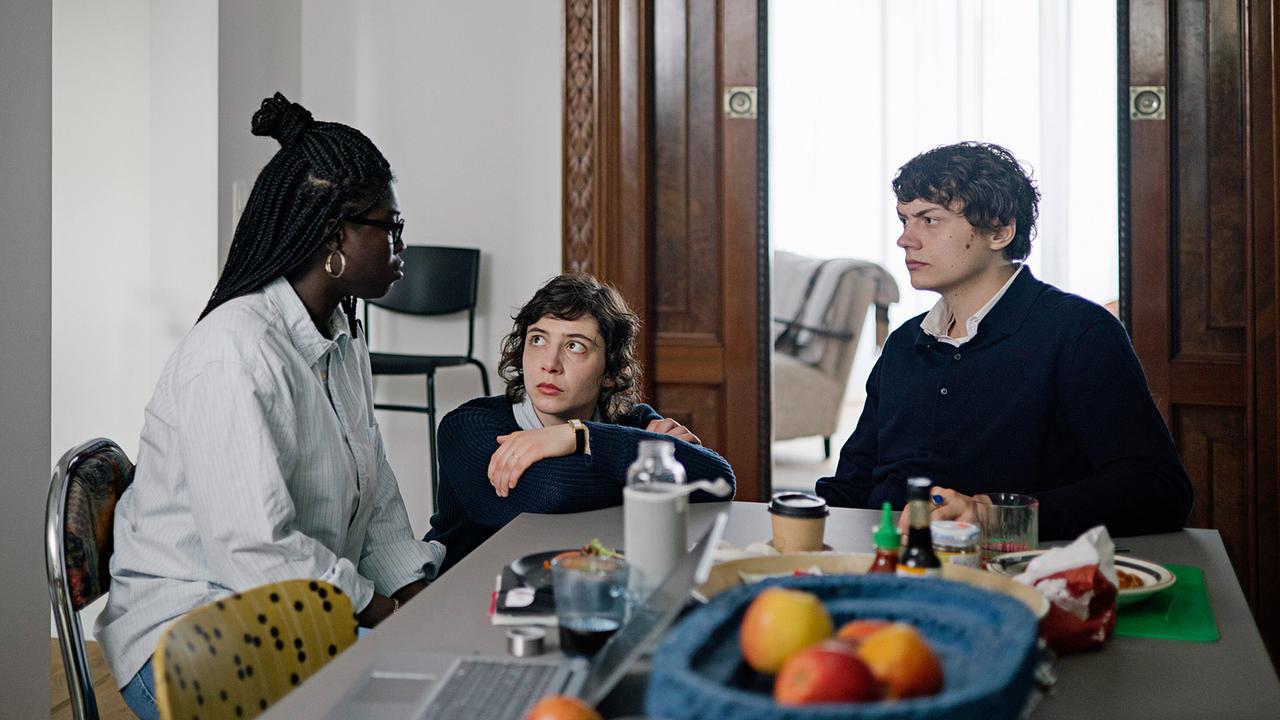 Laslo Wolf, Karima Al-Sharquawi und Hannes Butenbeker besprechen sich an einem Esstisch in ihrer WG.