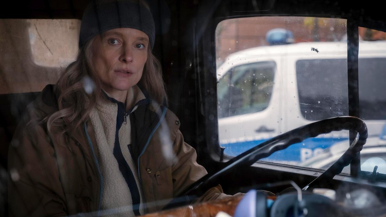 Prof. Dara Kimmerer am Steuer eines Kleinbusses, , draußen steht ein Polizeifahrzeug.