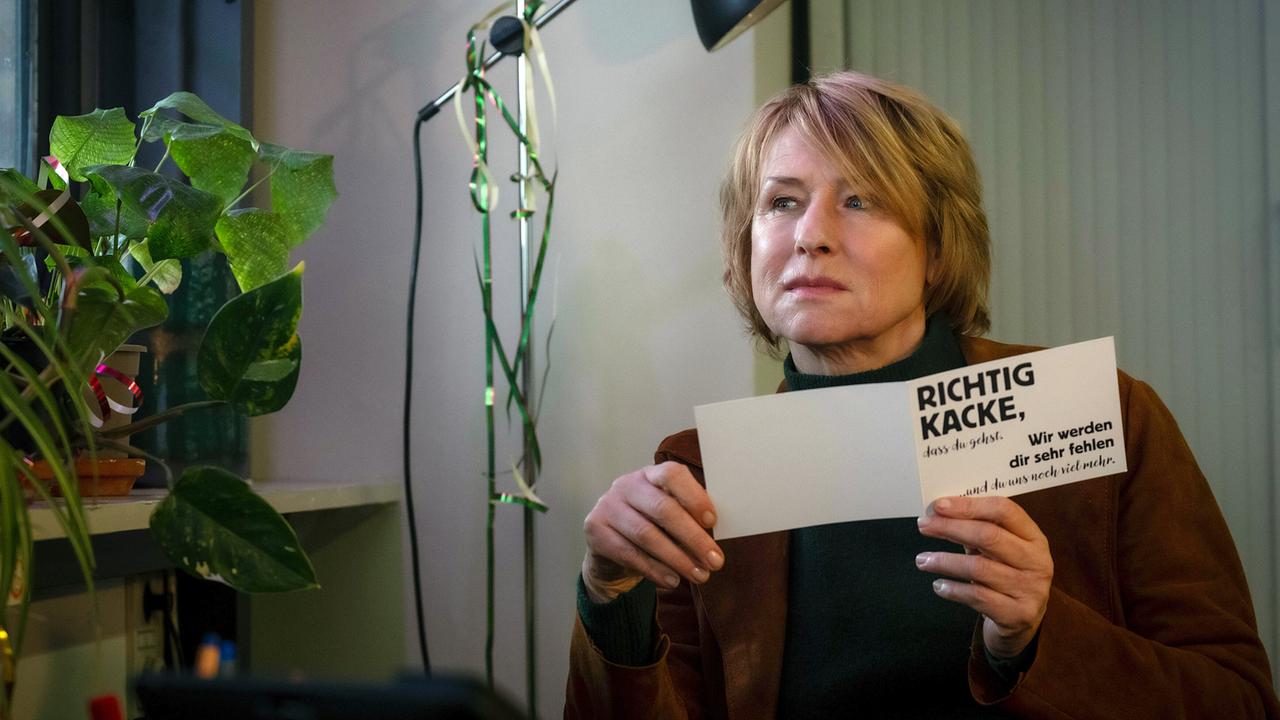 Susanne Bonard sitzt an ihrem letzten Tag im Büro der Mordkommission  und hält eine Karte mit einer schriftlichen Botschaft in den Händen.